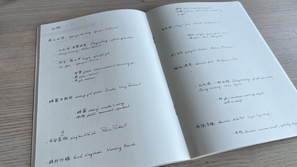 A notebook opened with handwritten notes, mostly Chinese vocabulary and name of game items.